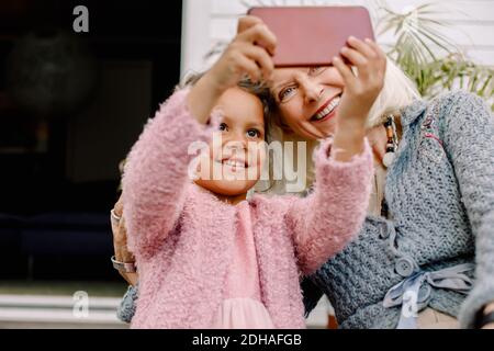 Nipote sorridente e nonna che prendono selfie nel telefono cellulare Foto Stock
