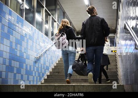 Tutta la lunghezza degli amici con i bagagli che saliscono sui gradini alla stazione della metropolitana Foto Stock