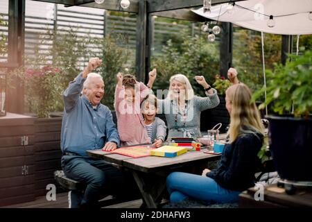 Allegro gioco da tavolo con la famiglia mentre si siede al tavolo cortile Foto Stock