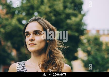 Close-up di pensosa giovane donna che guarda lontano in città Foto Stock