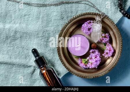 Piatto aromaterapico con spazio per la copia. Bottiglia di olio essenziale, una candela, un flaconcino per gli oli, e fiori vervani, top shot Foto Stock