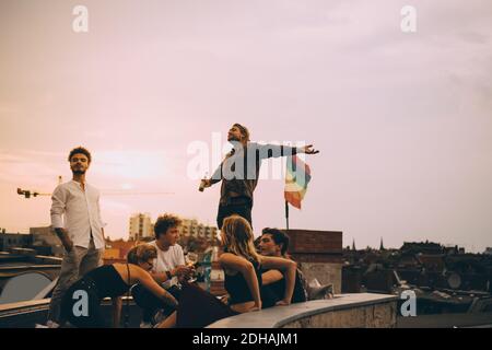 Uomo che gusta la birra mentre si rilassa con gli amici sulla terrazza a. festa sul tetto Foto Stock