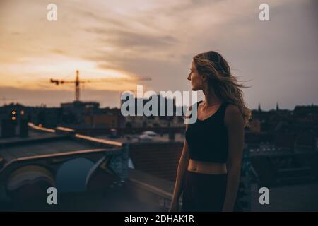 Donna premurosa che guarda via mentre si alza in terrazza durante la festa contro il cielo Foto Stock