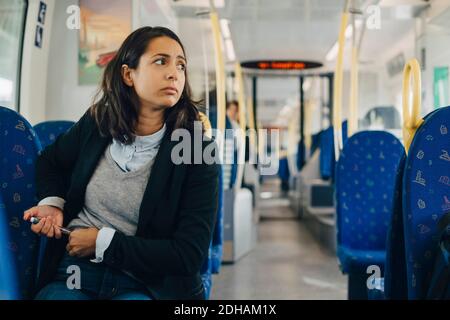 Donna che usa la penna per iniezione mentre si siede in treno Foto Stock