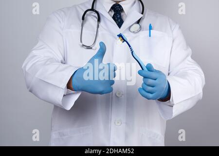 Il terapeuta medico è vestito in un abito bianco uniforme e. i guanti sterili blu sono in piedi e trattengono Foto Stock