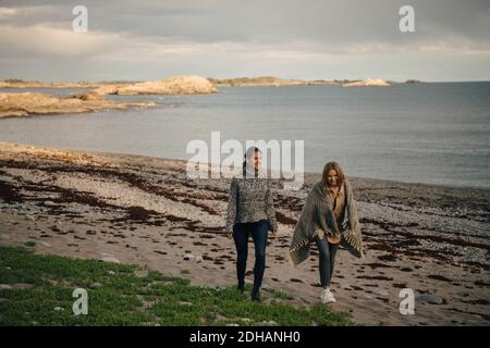 Una lunga serie di amici sorridenti che parlano mentre camminano in spiaggia Foto Stock
