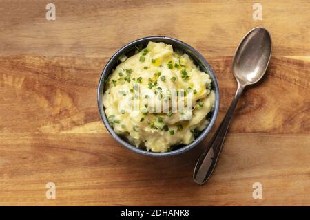 Purea di Pomme, una foto in alto di una ciotola di purè di patate con erbe, sparata dall'alto su uno sfondo rustico Foto Stock