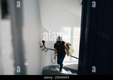 Vista ad alto angolo della borsa da trasporto donna e della racchetta da badminton mentre si arrampicano gradini in una nuova casa Foto Stock