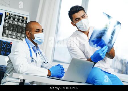 Due medici di sesso maschile esaminano la risonanza magnetica cerebrale di un paziente nel cabinet Foto Stock