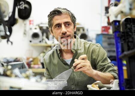 Uomo maturo che guarda via mentre lavora in officina Foto Stock