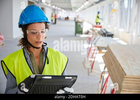 Giovane architetto femminile in abiti riflettenti utilizzando tablet digitale AT cantiere Foto Stock
