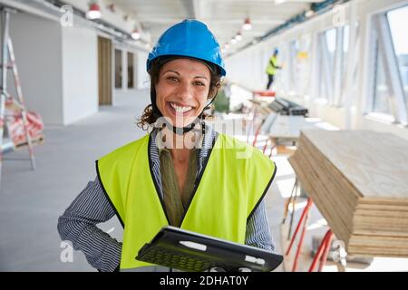 Ritratto di sorridente ingegnere femminile con tablet digitale in piedi cantiere Foto Stock