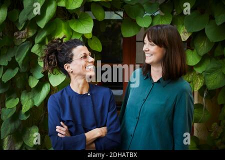 Sorridente architetti donne contro superriduttore piante in cortile Foto Stock