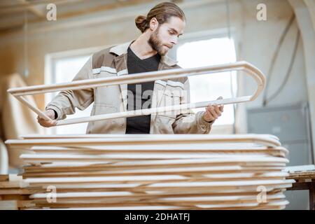 Bel falegname che controlla la qualità del telaio della finestra prima la vernice presso l'officina di falegnameria Foto Stock