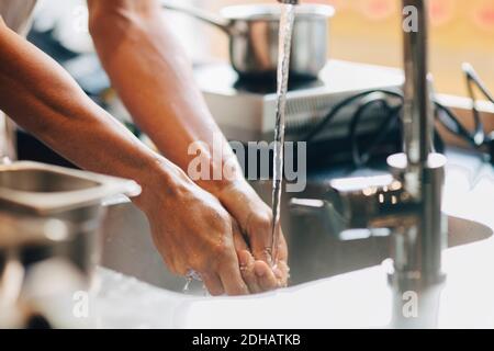 Immagine ritagliata dello chef maschile lavando le mani nel lavello a. cucina commerciale Foto Stock