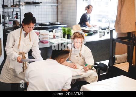 I proprietari di ristoranti multietnici discutono mentre si siedono al tavolo Foto Stock