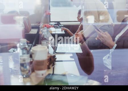 Donna d'affari che usa il telefono con la famiglia in background visto attraverso il treno finestra Foto Stock