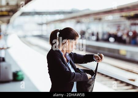 Donna d'affari matura che cerca in borsa alla stazione ferroviaria Foto Stock