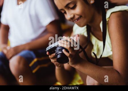 Sorridente ragazza che guarda la macchina fotografica mentre si siede con il fratello a. stazione Foto Stock