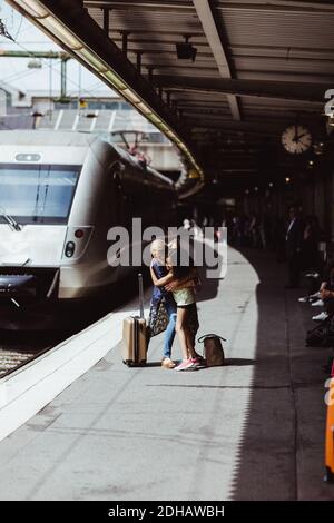 Felice madre e figlia abbracciare mentre salutano alla stazione ferroviaria Foto Stock