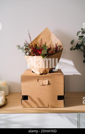 Elegante bouquet fiore arrangiamento da fiorista in una scatola preparata per il trasporto su un tavolo di legno Foto Stock