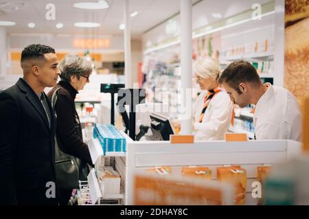 Clienti e farmacisti al momento del check-out in un negozio medico Foto Stock