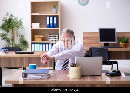 Anziano dipendente di sesso maschile che soffre di radiculite sul posto di lavoro Foto Stock