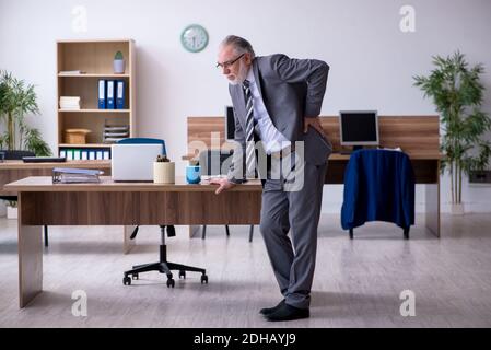 Anziano dipendente di sesso maschile che soffre di radiculite sul posto di lavoro Foto Stock