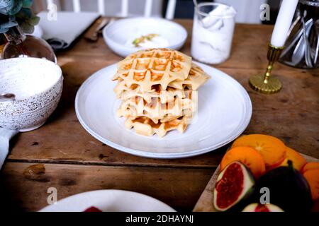 Primo piano ad alta angolazione con waffle impilati in un piatto di legno tabella Foto Stock