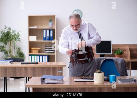 Anziano dipendente di sesso maschile che soffre di radiculite sul posto di lavoro Foto Stock