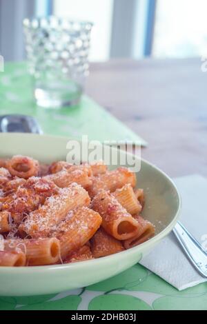 Un piatto di cucina italiana: I Rigatoni (a forma di pasta) con salsa di pomodoro e formaggio Grana Padano grattugiato Foto Stock