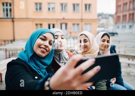 Giovane donna che prende selfie con le amiche musulmane in città Foto Stock