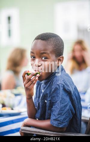 Ritratto del ragazzo sorridente che mangia l'anguria alla festa in giardino Foto Stock