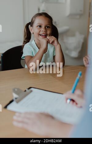 Sorridente ragazza che parla con il medico durante l'esame medico in ospedale Foto Stock
