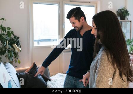 Giovane coppia che sceglie la pittura sul divano a casa Foto Stock