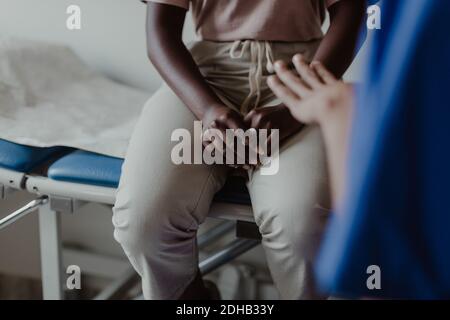 Sezione centrale dell'operatrice sanitaria femminile che spiega ai giovani pazienti dentro clinica medica Foto Stock