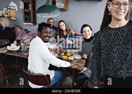 Allegri amici multietnici che si gustano il brunch al ristorante Foto Stock