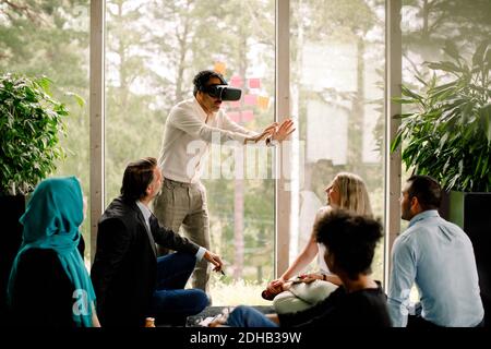 Uomo d'affari che indossa un simulatore di realtà virtuale durante la conferenza con i colleghi a. centro congressi Foto Stock