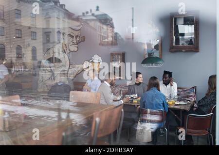 Le persone che si godono il brunch al ristorante visto attraverso la finestra di vetro Foto Stock