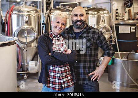 Ritratto di sorridenti partner maschili e femminili in piedi in birreria Foto Stock