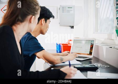 Giovane donna seduta da un uomo che usa un computer portatile in classe a. università Foto Stock