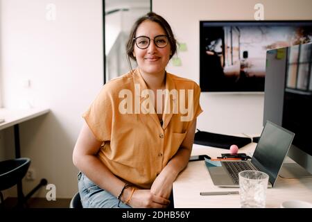 Ritratto di donna d'affari sorridente seduto alla scrivania in ufficio Foto Stock