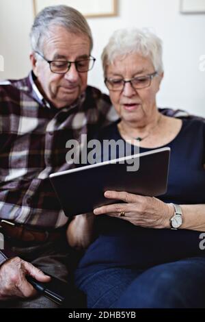 Coppia senior che condivide il tablet digitale con la parete a casa Foto Stock