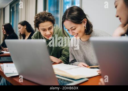 Ragazzi sorridenti che studiano alla scrivania a scuola Foto Stock