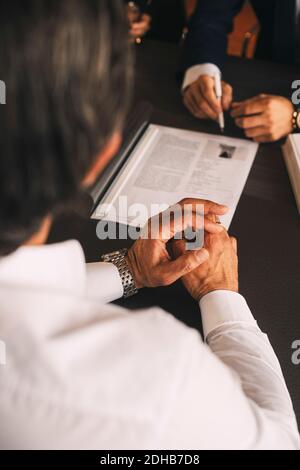 Vista ad alto angolo di un uomo d'affari che discute su un documento in riunione in ufficio Foto Stock