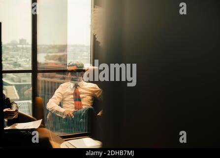 Avvocato maturo seduto con un collega nella sala di amministrazione in ufficio Foto Stock