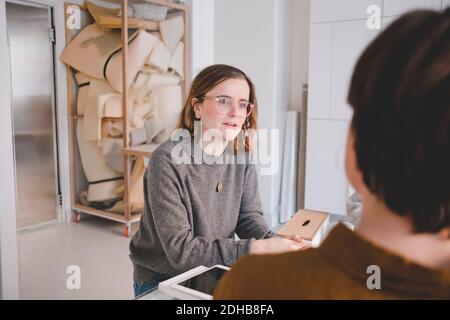 Giovane imprenditore femminile che discute con la collega in laboratorio di tappezzeria Foto Stock