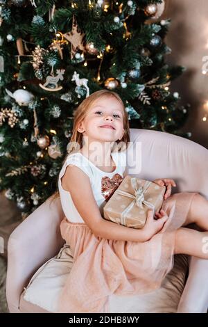 Bella bambina con regalo vicino albero di Natale a casa Foto Stock