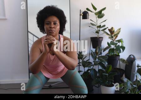 Ritratto di donna afroamericana in abbigliamento sportivo allenarsi. Autoisolamento fitness a casa durante la pandemia di coronavirus covid 19. Foto Stock