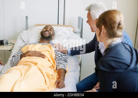 Padre incoraggiando il figlio mentre si siede a letto nel reparto dell'ospedale Foto Stock